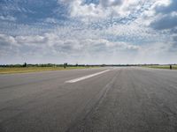 a view of an airplane landing on the runway under clouds in a bright blue sky