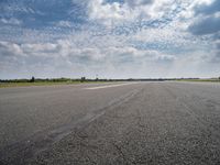 a view of an airplane landing on the runway under clouds in a bright blue sky