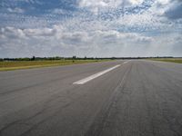 a view of an airplane landing on the runway under clouds in a bright blue sky