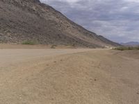 a small vehicle traveling across a barren road between some large rocks and boulders on one side