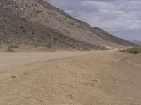 a small vehicle traveling across a barren road between some large rocks and boulders on one side