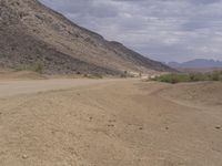 a small vehicle traveling across a barren road between some large rocks and boulders on one side