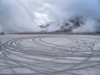 a view from a snowy mountain top with a circular tire on the road surface surrounded by fog and low clouds