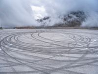 a view from a snowy mountain top with a circular tire on the road surface surrounded by fog and low clouds