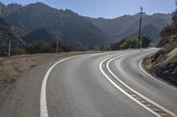 two white lines painted on the road with mountains in the background and a sun shining