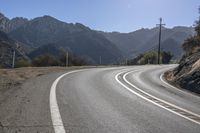 two white lines painted on the road with mountains in the background and a sun shining