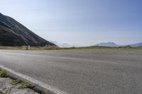 a motorcycle parked on a small mountain side road near mountains with no cars driving on it