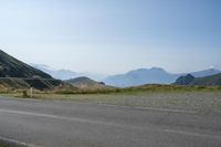 a motorcycle parked on a small mountain side road near mountains with no cars driving on it