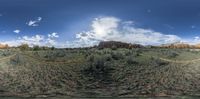 a panoramic view of a valley with green grass and mountains in the distance