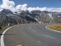 a paved road with mountains in the background with no cars to drive along in the foreground