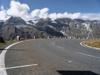 a paved road with mountains in the background with no cars to drive along in the foreground