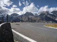 a paved road with mountains in the background with no cars to drive along in the foreground