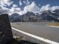 a paved road with mountains in the background with no cars to drive along in the foreground