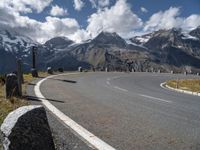 a paved road with mountains in the background with no cars to drive along in the foreground