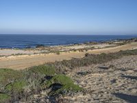 a view of a sandy beach and a sandy road, where an orange sign is located