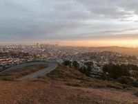 the view of a road running through a city skyline towards the horizon at sunset with a winding curve