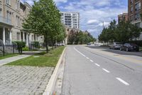 a road with a sidewalk with white markings next to two building with brown and beige trim