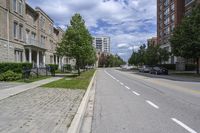 a road with a sidewalk with white markings next to two building with brown and beige trim