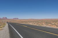 a road stretching out into the distance in the desert with mountains in the background as seen from the roadside