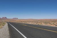 a road stretching out into the distance in the desert with mountains in the background as seen from the roadside