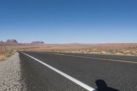 a road stretching out into the distance in the desert with mountains in the background as seen from the roadside