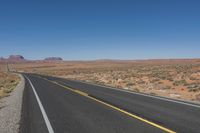a road stretching out into the distance in the desert with mountains in the background as seen from the roadside