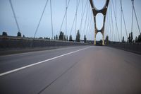 a view from behind of a moving car on the bridge in a city at dusk