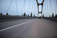 a view from behind of a moving car on the bridge in a city at dusk