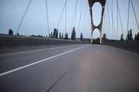 a view from behind of a moving car on the bridge in a city at dusk