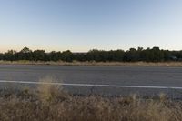 a long empty road with mountains in the distance with a car in the foreground