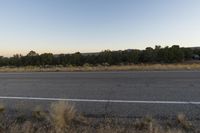 a long empty road with mountains in the distance with a car in the foreground