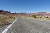 two lanes leading away through the desert, in the middle of the day and in the distance is a mountain range