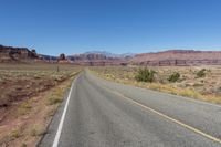 two lanes leading away through the desert, in the middle of the day and in the distance is a mountain range