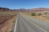 two lanes leading away through the desert, in the middle of the day and in the distance is a mountain range