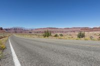 two lanes leading away through the desert, in the middle of the day and in the distance is a mountain range