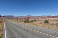 two lanes leading away through the desert, in the middle of the day and in the distance is a mountain range