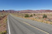 two lanes leading away through the desert, in the middle of the day and in the distance is a mountain range