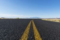 the long road is lined with black pebbles and yellow stripes the middle has white clouds