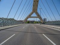 a truck driving across a bridge near a street corner near buildings and a bridge with many cables