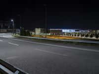 an empty freeway at night and buildings in the background by night sky with street lights