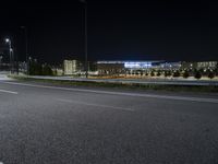 an empty freeway at night and buildings in the background by night sky with street lights