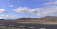 two different road lanes going around mountains in the distance with a sky background and a cloudy sky