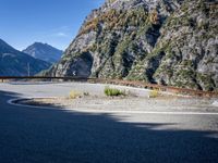 mountains and road side with no traffic on it in europes alps wilderness area with a winding curve