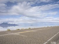 a lone motorcycle sitting on the side of a road near the ocean in front of a mountainous landscape