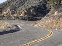 the empty roadway with curve in the middle is very steep terrain and mountain views appear to be in the background