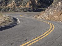 the empty roadway with curve in the middle is very steep terrain and mountain views appear to be in the background