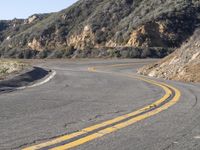 the empty roadway with curve in the middle is very steep terrain and mountain views appear to be in the background