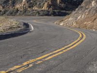 the empty roadway with curve in the middle is very steep terrain and mountain views appear to be in the background