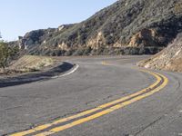 the empty roadway with curve in the middle is very steep terrain and mountain views appear to be in the background