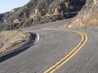 the empty roadway with curve in the middle is very steep terrain and mountain views appear to be in the background